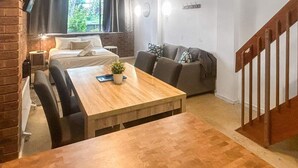 Una habitació acollidora amb una taula de dinar de fusta, un sofà i una escala.