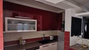 Une cuisine moderne avec des meubles de rangement rouges et blancs, un four à micro-ondes encastré et un lave-vaisselle.