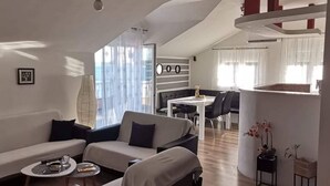 Un salon moderne comprenant un ensemble de canapés, une table à manger avec des chaises et un coin cuisine.