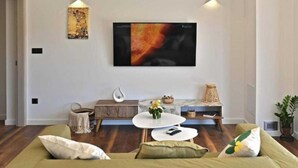 A modern living room with a green sofa, a white coffee table, and a flat-screen TV mounted on the wall.