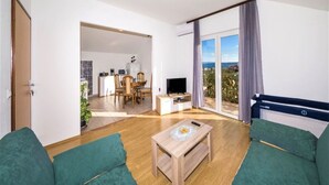 Un salon moderne avec un canapé, une table basse, un téléviseur et un balcon offrant une vue agréable.