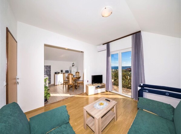 A modern living room with a sofa, a coffee table, a TV, and a balcony with a view.