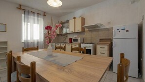 A compact kitchen with a dining table, chairs, a microwave, stove, and a refrigerator. - Three Bedroom Holiday Home (Vinisce)