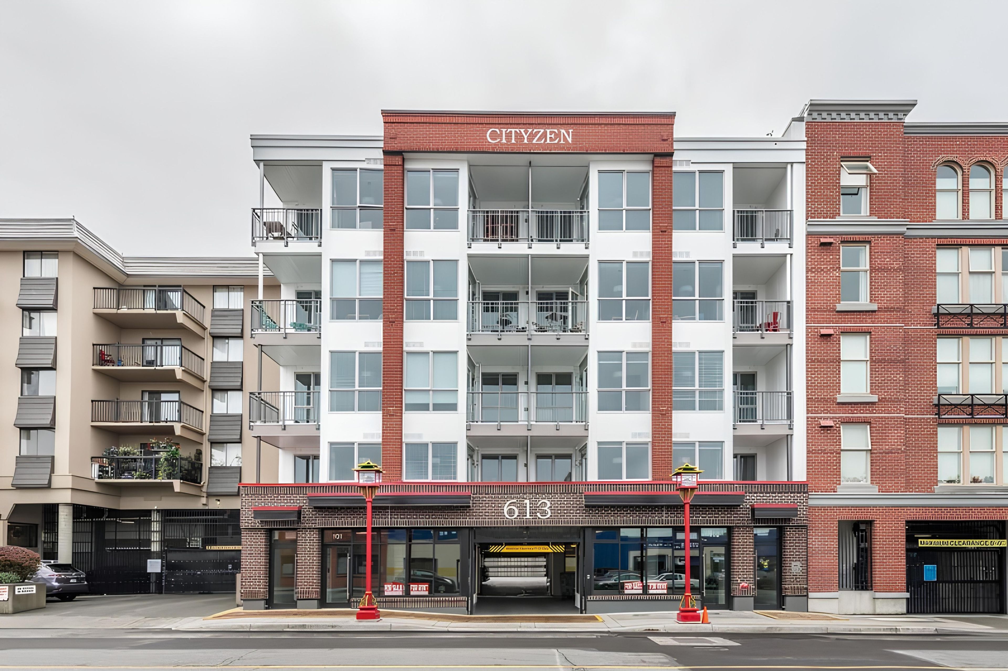 A multi-story building with a prominent 'CITIZEN' sign, featuring a brick facade, multiple balconies, and a ground-level commercial space with a storefront.