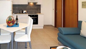 A compact living space with a dining area, kitchenette, and a sofa. - Sea-View Apartments with Pool, Terrace, and Outdoor Lounge in Scenic Čiovo Island - Comfort One Bedroom Apartment (Ciovo)