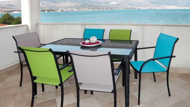 A terrace with a glass table and chairs, overlooking a body of water and a distant cityscape. - Sea-View Apartments with Pool, Terrace, and Outdoor Lounge in Scenic Čiovo Island - Two Bedroom Apartment (Ciovo)