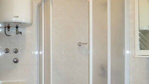A bathroom with a toilet, a shower enclosure, and a sink. - Sea-View Apartments with Pool, Terrace, and Outdoor Lounge in Scenic Čiovo Island - Two Bedroom Apartment (Ciovo)