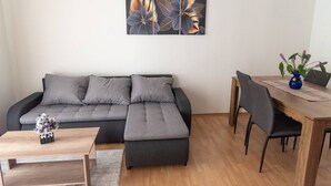 Una sala de estar moderna con un sofá seccional gris, una mesa de centro de madera y un comedor con mesa y sillas de madera.