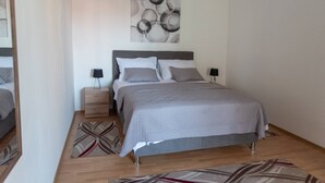 Un dormitorio moderno con cama, mesitas de noche y una obra de arte abstracta en la pared.