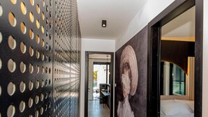 A hallway with a perforated metal wall, a large painting, and a bed with a window view. - Four Bedroom Villa with pool (Vodice)