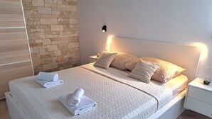 A neatly made bed with a quilted white cover, two pillows, and two folded towels. - Hillside Villa in Trogir with Pool, Terrace, and Stunning City View - Three Bedroom Villa (Trogir)