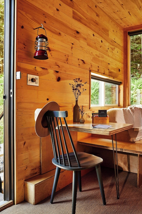 Un interior de madera con una mesa, una silla y un farol colgante.