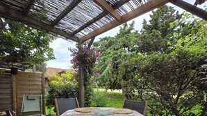 An outdoor patio with a round table, four chairs, and a pergola structure.