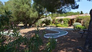 A garden with a winding water feature, surrounded by trees and shrubs.