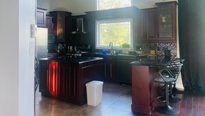 Una cocina moderna con armarios oscuros, una isla central y una zona de bar con taburetes.