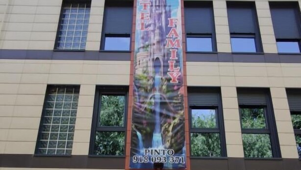 Ein Gebäude mit einem vertikalen Banner, das ein Hotel namens "Hostel Family" und eine Kontaktnummer bewirbt.