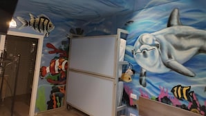 Ein Zimmer mit Wandgemälde von Meereslebewesen, einer Dusche und einem kleinen Kühlschrank.