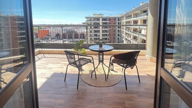A balcony with a table and chairs, a view of surrounding buildings, and a clear sky. - One stop away from FCO Airport and Fiera di Roma. Complete with all amenities (Lazio)