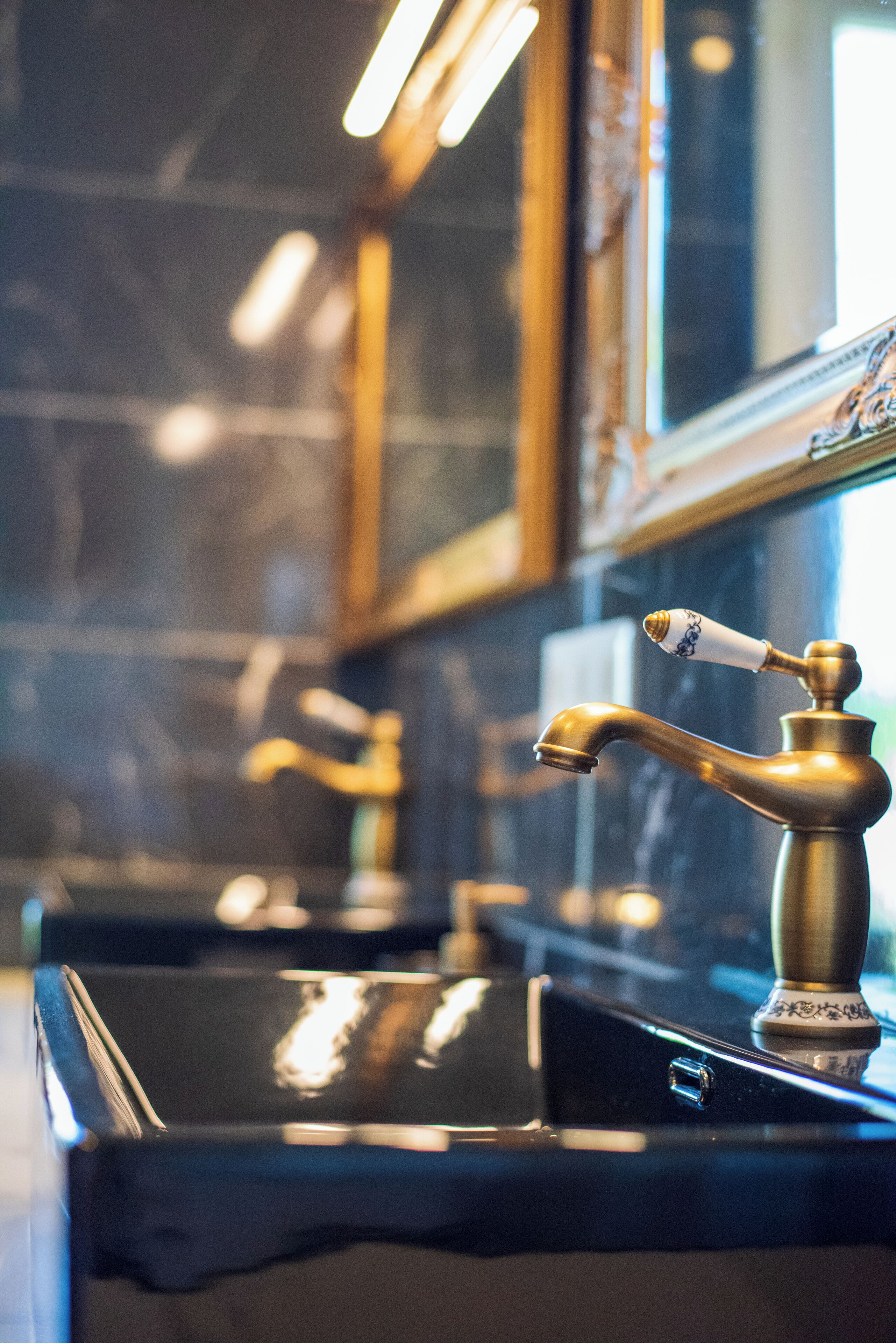 Une salle de bain avec un lavabo noir et un robinet doré.