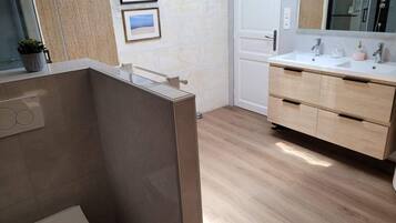 Ein modernes Badezimmer mit einem Holzbadezimmerhocker, einem großen Spiegel und zwei gerahmten Bildern an der Wand.