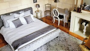 Ein Schlafzimmer mit Bett, Schreibtisch, Stuhl, Kamin und einem gerahmten Bild an der Wand.