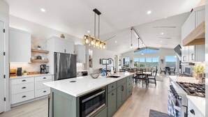 A spacious kitchen with a large island, modern appliances, and a view to the outdoors. - Lakefront Retreat: Swim Spa & Backyard Lake Access! Relax & Play; 2 King Suites (Lago Vista)