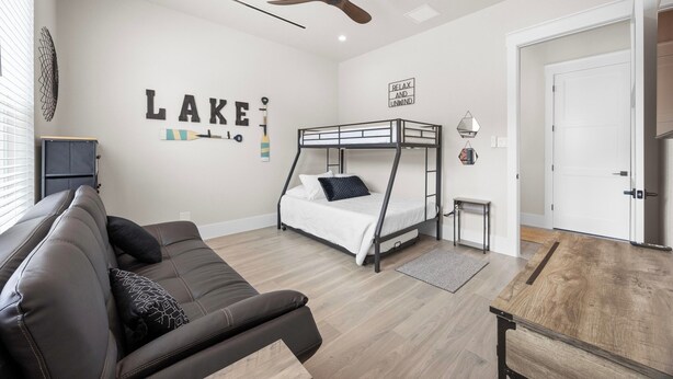 A modern bedroom with a bunk bed, a sofa, a ceiling fan, and a wall with motivational text. - Lakefront Retreat: Swim Spa & Backyard Lake Access! Relax & Play; 2 King Suites (Lago Vista)