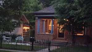 A small brick house with a porch, a fenced yard, and a bench. - Updated Charming Victorian in Old Town near CSU!  (Fort Collins)