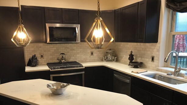 A modern kitchen with dark cabinets, a stainless steel microwave, a gas stove, and a white marble countertop. - Updated Charming Victorian in Old Town near CSU!  (Fort Collins)