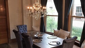 A dining area with a chandelier, dark curtains, and a view of greenery outside. - Updated Charming Victorian in Old Town near CSU!  (Fort Collins)