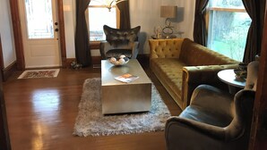 A living room with a sofa, armchair, coffee table, and a chandelier. - Updated Charming Victorian in Old Town near CSU!  (Fort Collins)