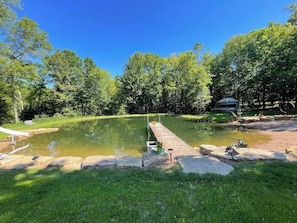 A tranquil outdoor setting with a pond, a wooden dock, and a gazebo.