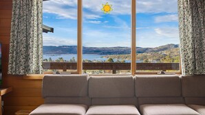 Ein Zimmer mit einem großen Fenster, das einen malerischen Ausblick bietet, einer hölzernen Bank und Vorhängen mit einem Blumenmuster.