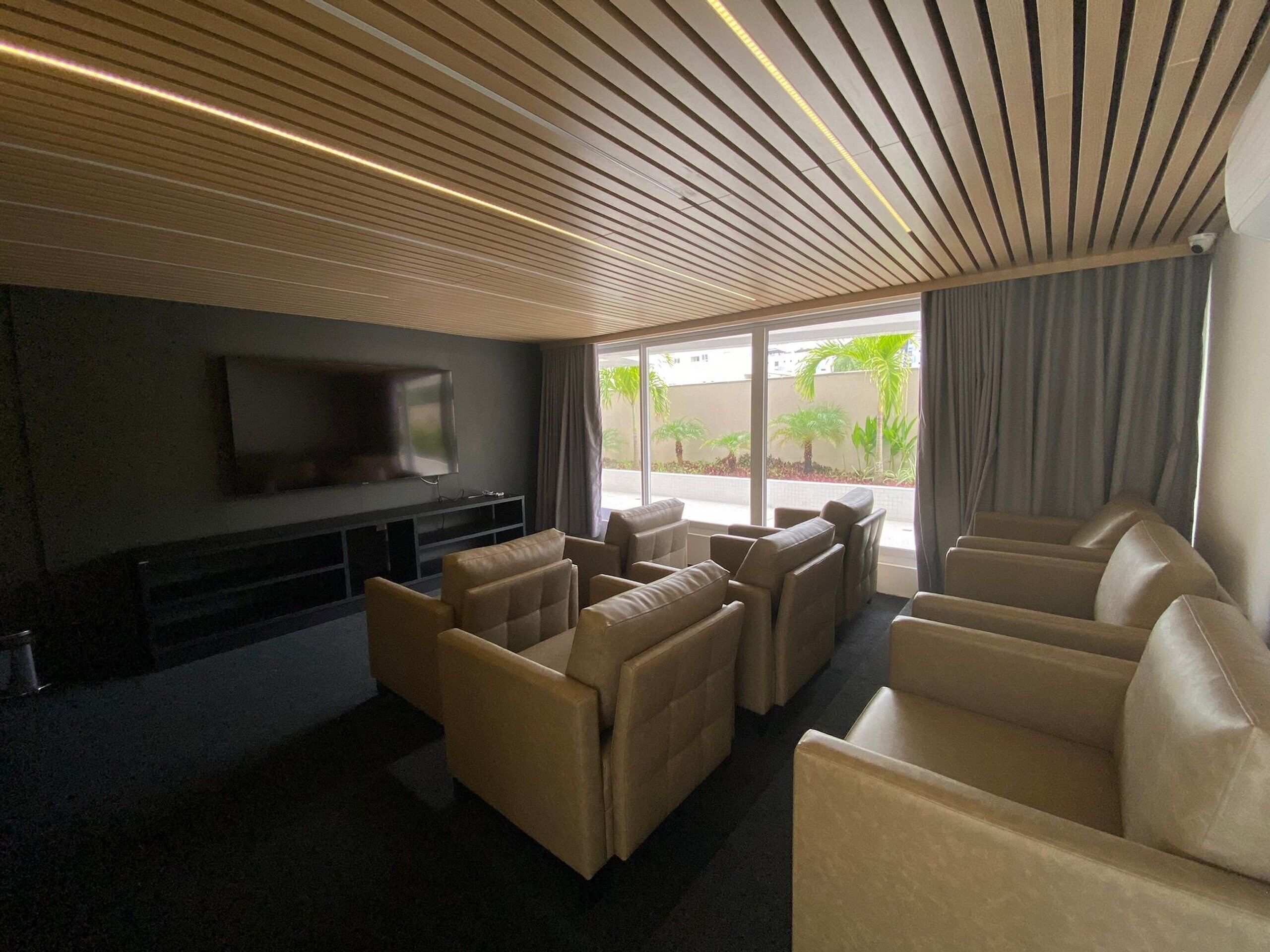 Un soggiorno moderno con una TV a schermo piatto, divani in pelle e un soffitto con linee orizzontali.