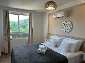 Ein Hotelzimmer mit Bett, einem Fenster mit Vorhängen, einer Klimaanlage und einer Wanddekoration.