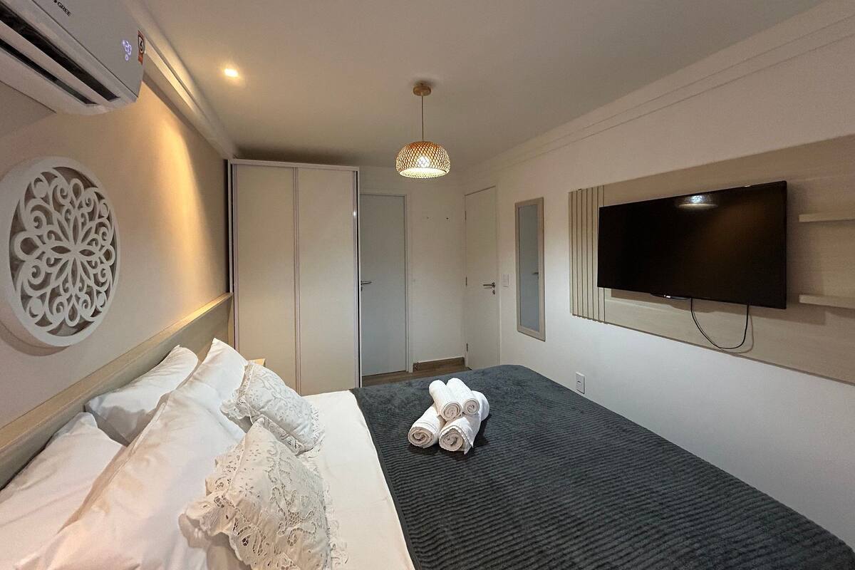 Une chambre d’hôtel équipée d’un lit, d’un téléviseur fixé au mur, d’un luminaire au plafond et d’un appareil de climatisation.