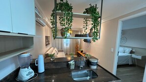 Una cocina moderna con un lavamanos integrado, una licuadora en la encimera y plantas colgantes.