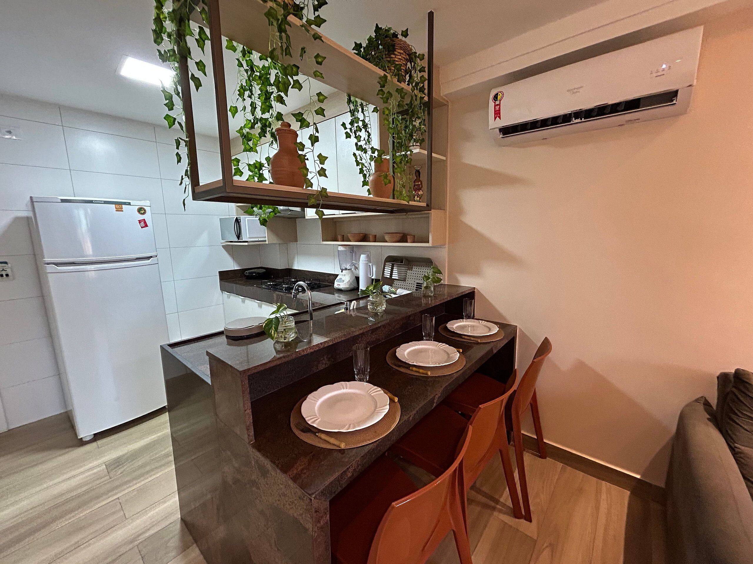 A kitchen with a refrigerator, stove, sink, and a dining area with chairs and a table.