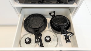 Een keukula naar twee koekenpannen, een braadpan en een glazen deksel.