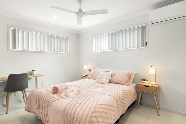 Un dormitorio con cama, mesitas de noche, un escritorio y una silla.