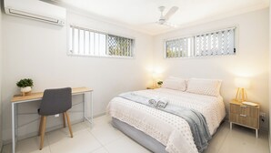 A bedroom with a bed, desk, chair, bedside tables, and a ceiling fan. - Covered Parking | 1 Bdr Apt w/ AC | 435AF1 (Rocklea)