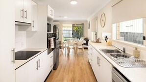 Una cocina moderna con armarios blancos, electrodomésticos de acero inoxidable y piso de madera.