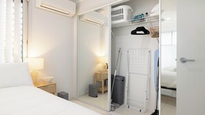 A bedroom with a bed, bedside table, lamp, and a closet with a mirror. - 1 Bdr Apt w/ AC & Kitchen | Parking | 316F1 (Rocklea)