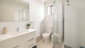 A modern bathroom with a white sink, mirror, toilet, and glass shower enclosure. - 1 Bdr Apt w/ AC | Kitchen | Parking | 131AF1 (Rocklea)