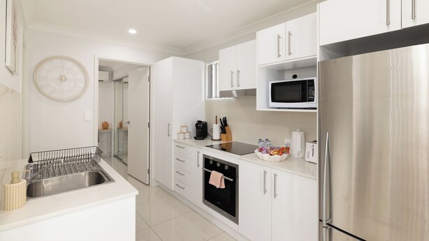 A modern kitchen with white cabinets, stainless steel appliances, and a built-in oven. - 1 Bdr Apt w/ AC | Kitchen | Parking | 131AF1 (Rocklea)