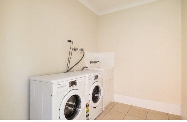 A laundry room with two white washing machines and a white cabinet.