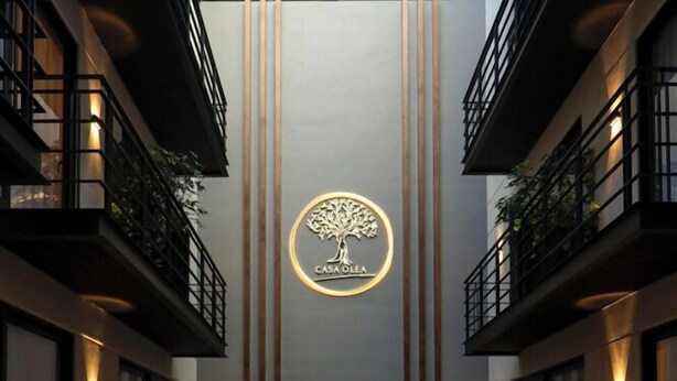 Un atrio moderno con una zona de estar central, lámparas colgantes y un logotipo en la pared.