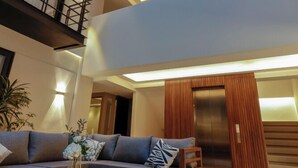 Un interior moderno con un sofá seccional, una mesa de centro redonda y una escalera que conduce a un nivel superior.