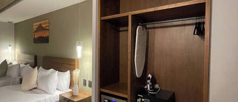 Una habitación de hotel con cama, mesita de noche y un armario de madera.