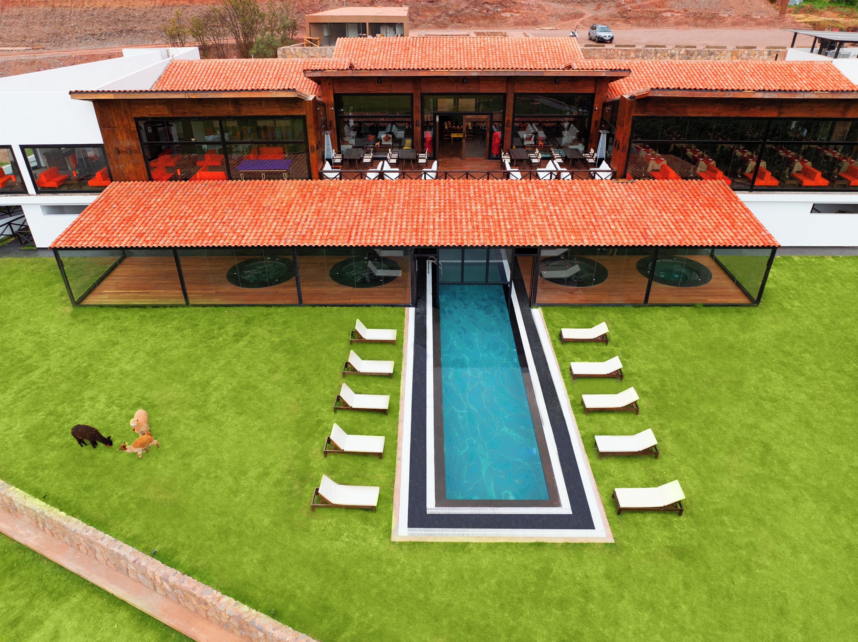 A modern building with a swimming pool, outdoor seating, and a covered patio area.